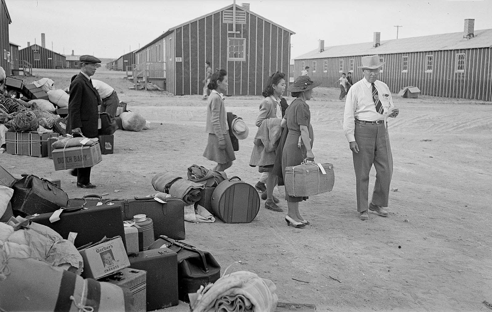 Employee Roy Kohn leads the Fujiwara family to their assigned quarters. MS 89 Jack Richard Photograph Collection, McCracken Research Library. PN.89.111.21236.9