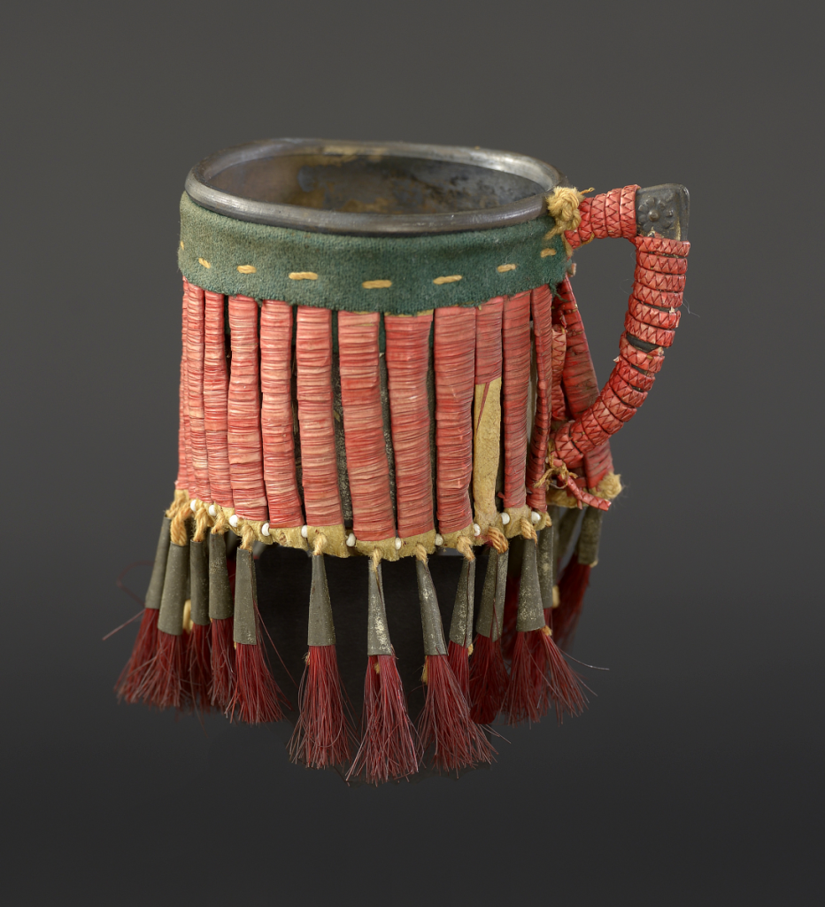  Cup, Lakota (Sioux), Northern Plains, ca.1900. Metal, rawhide, tin cones, glass beads, porcupine quills, tanned hide, wool cloth, cotton thread, dyed horse hair; NA.506.146. Courtesy of the Plains Indian Museum.