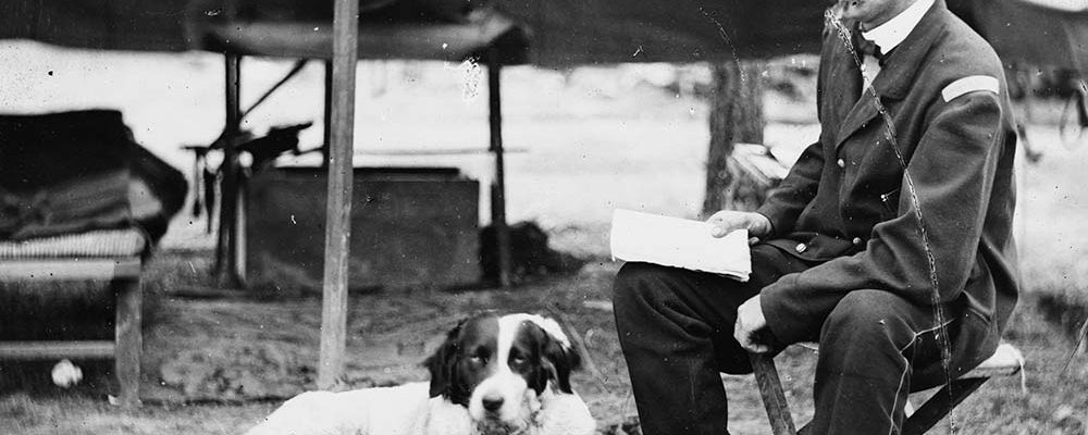 George Armstrong Custer in camp during the summer of 1862 with a gun dog lounging on a rug. Prints & Photographs, Library of Congress, LC-B811-2344.