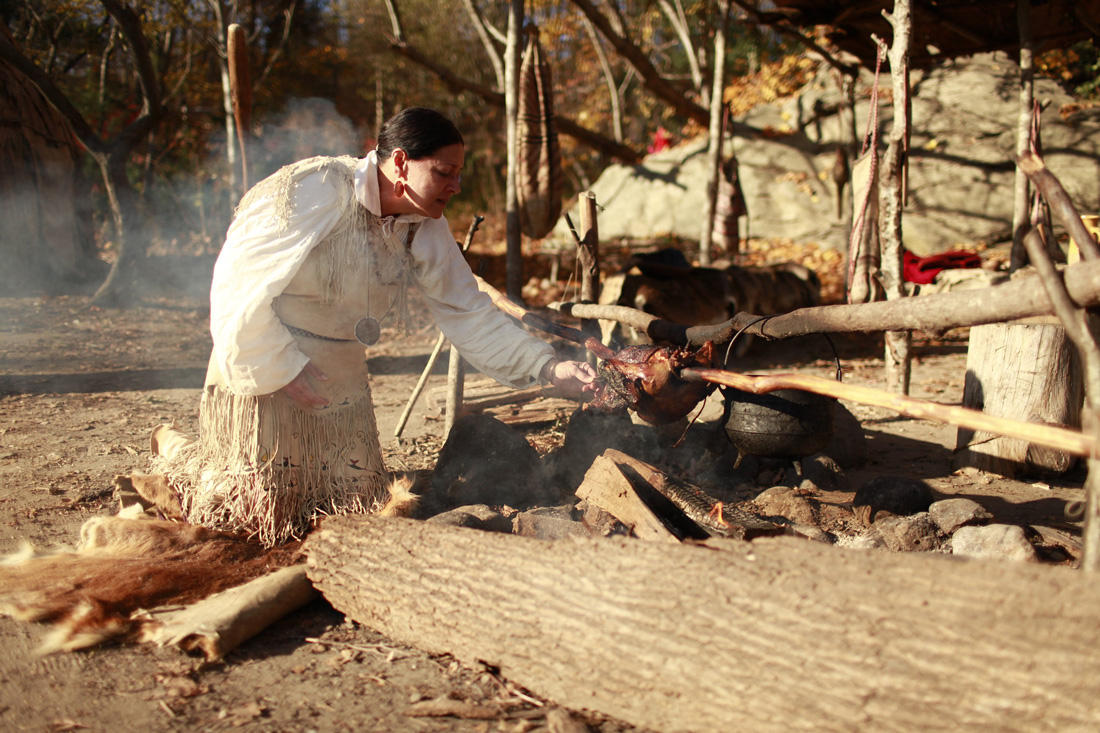 A reenactment presented as a living history exhibit of how turkeys were roasted on a stick over a fire. 