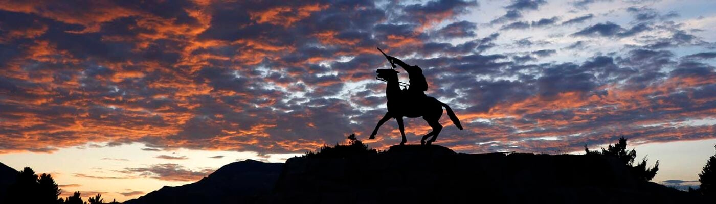 “Buffalo Bill—The Scout” sculpture by Gertrude Vanderbilt Whitney, silhouetted against a sunset sky. 3.58